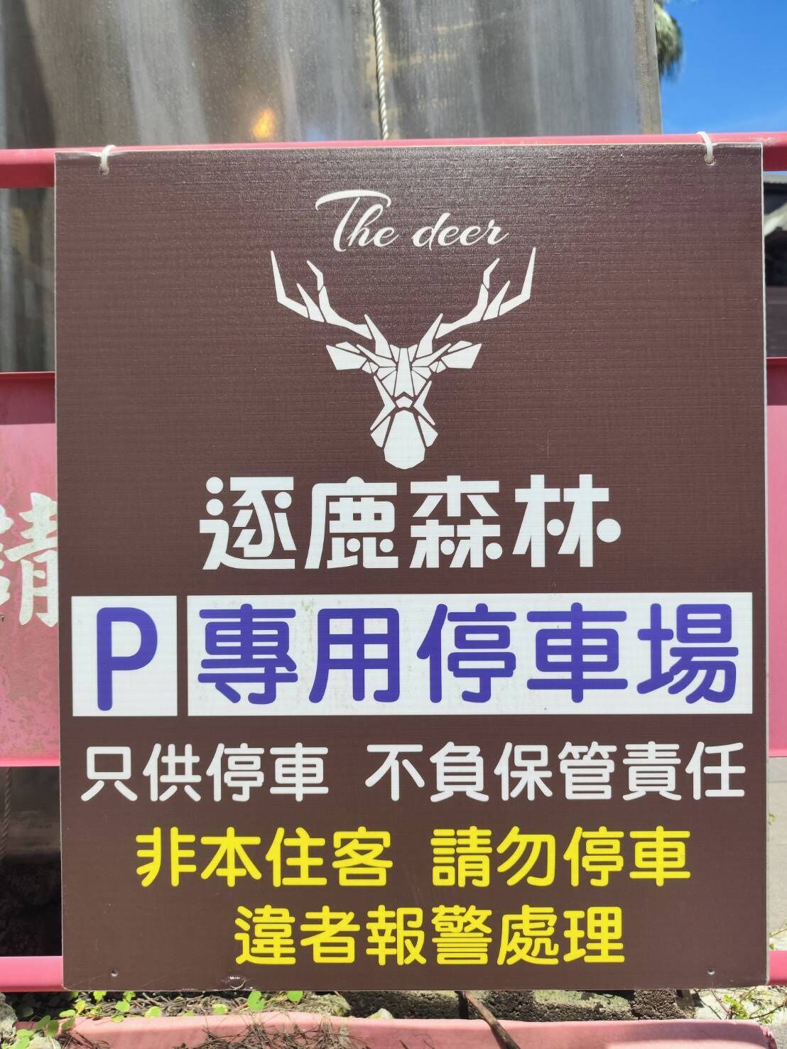 A parking sign with a deer logo and text in multiple languages, indicating a specialized parking area.
