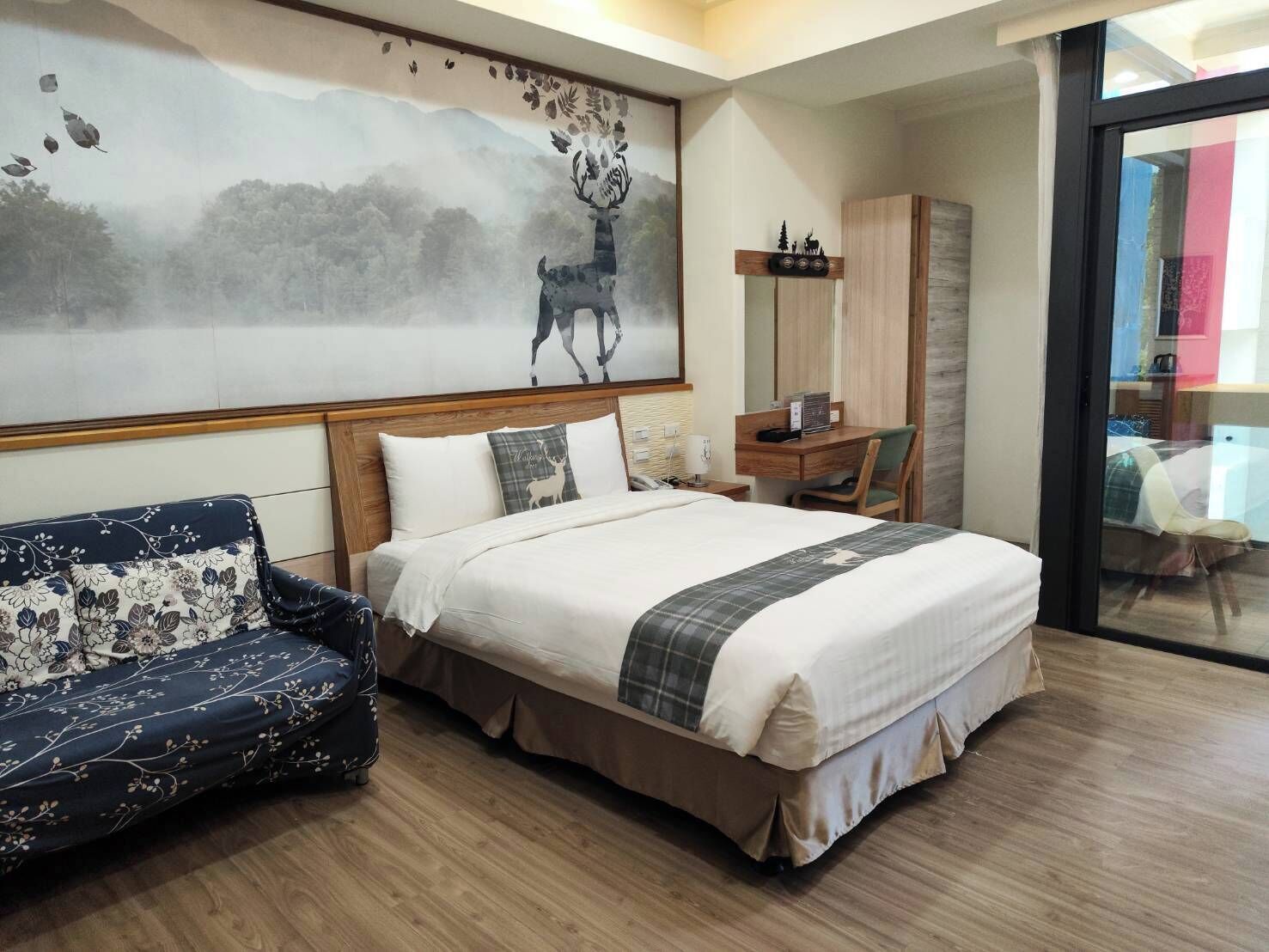 Een hotelkamer met een bed, een bureau, een stoel en een groot schilderij aan de muur.