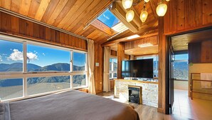 A room with a large bed, a TV, a fireplace, and a view of mountains. - Top Cloud Villa (Ren'ai)
