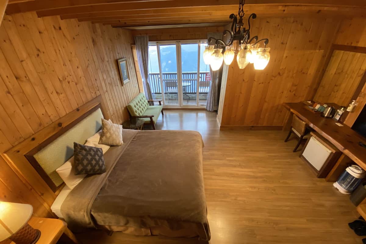 A cozy wooden cabin room with a bed, a small table, a bench, and a kitchenette.
