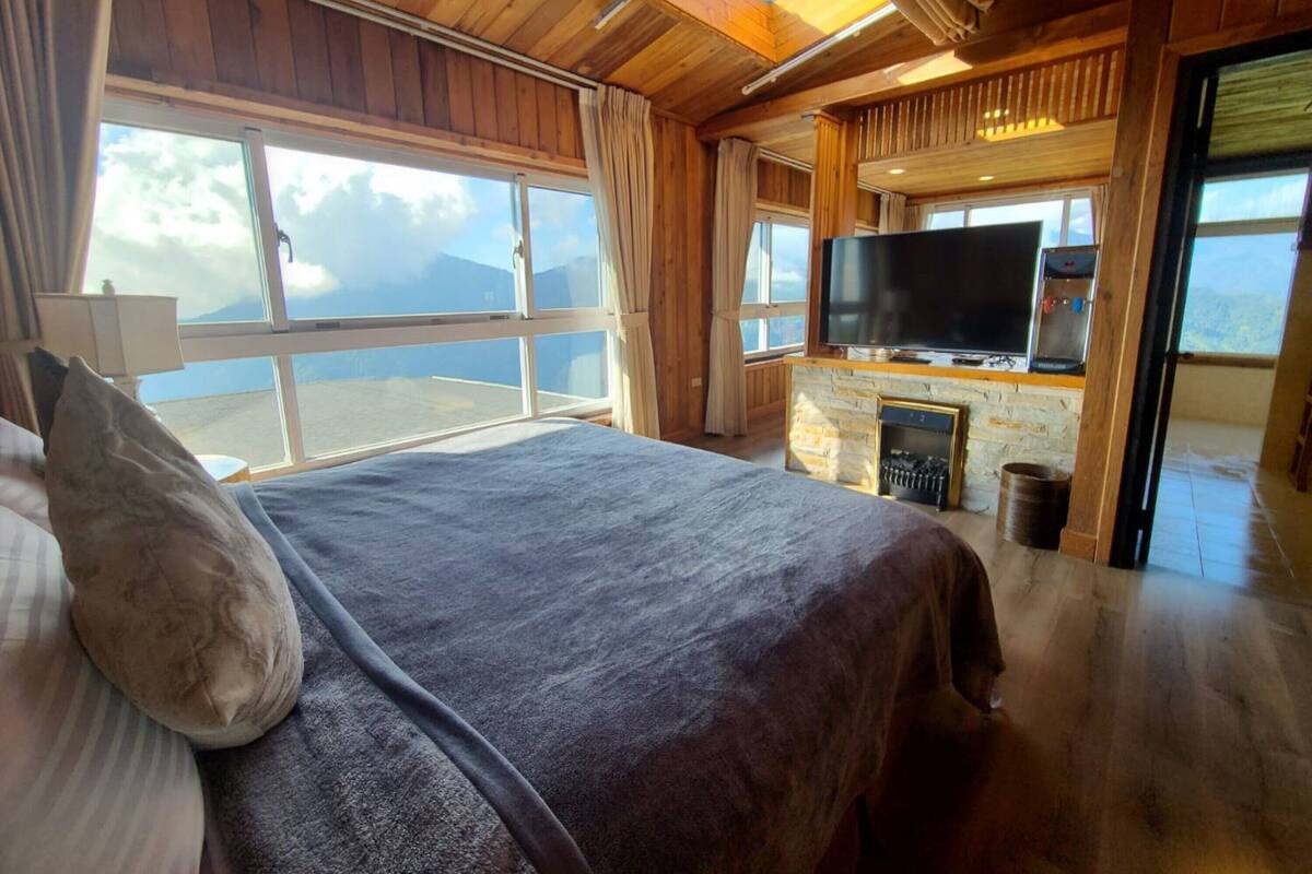 A bedroom with a large bed, a TV, and a fireplace.