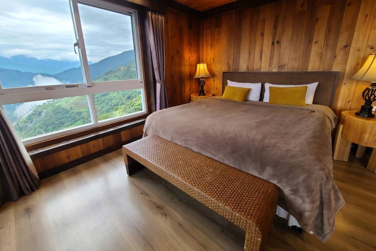 A wooden-paneled bedroom with a large window offering a mountain view.