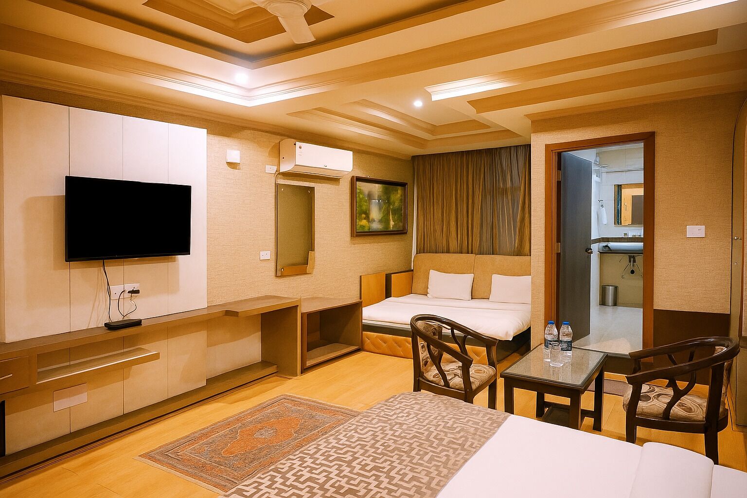 A hotel room with a bed, a desk, a chair, a television, and a bathroom visible through an open door.