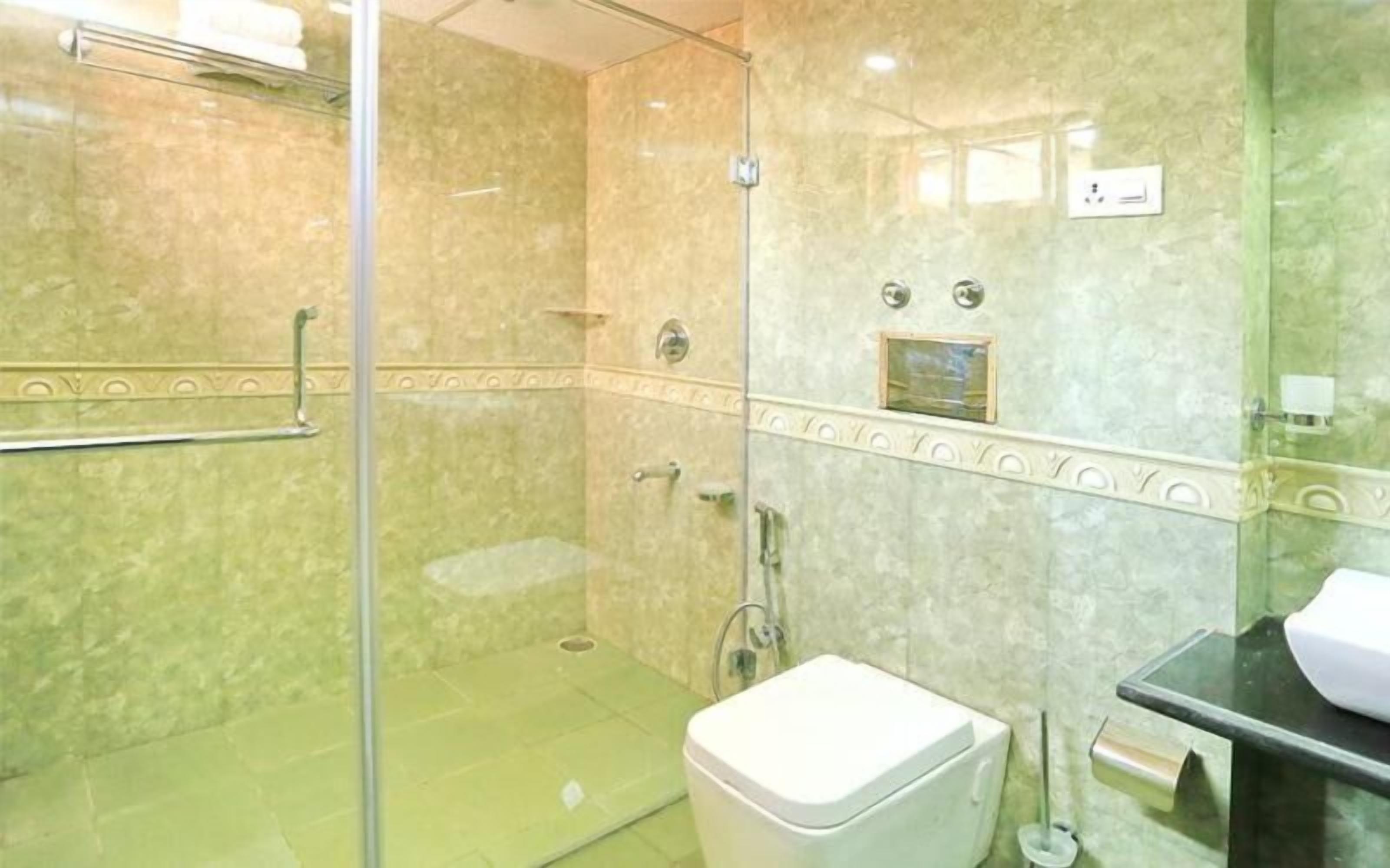 A bathroom with a glass shower enclosure, a toilet, and a sink.