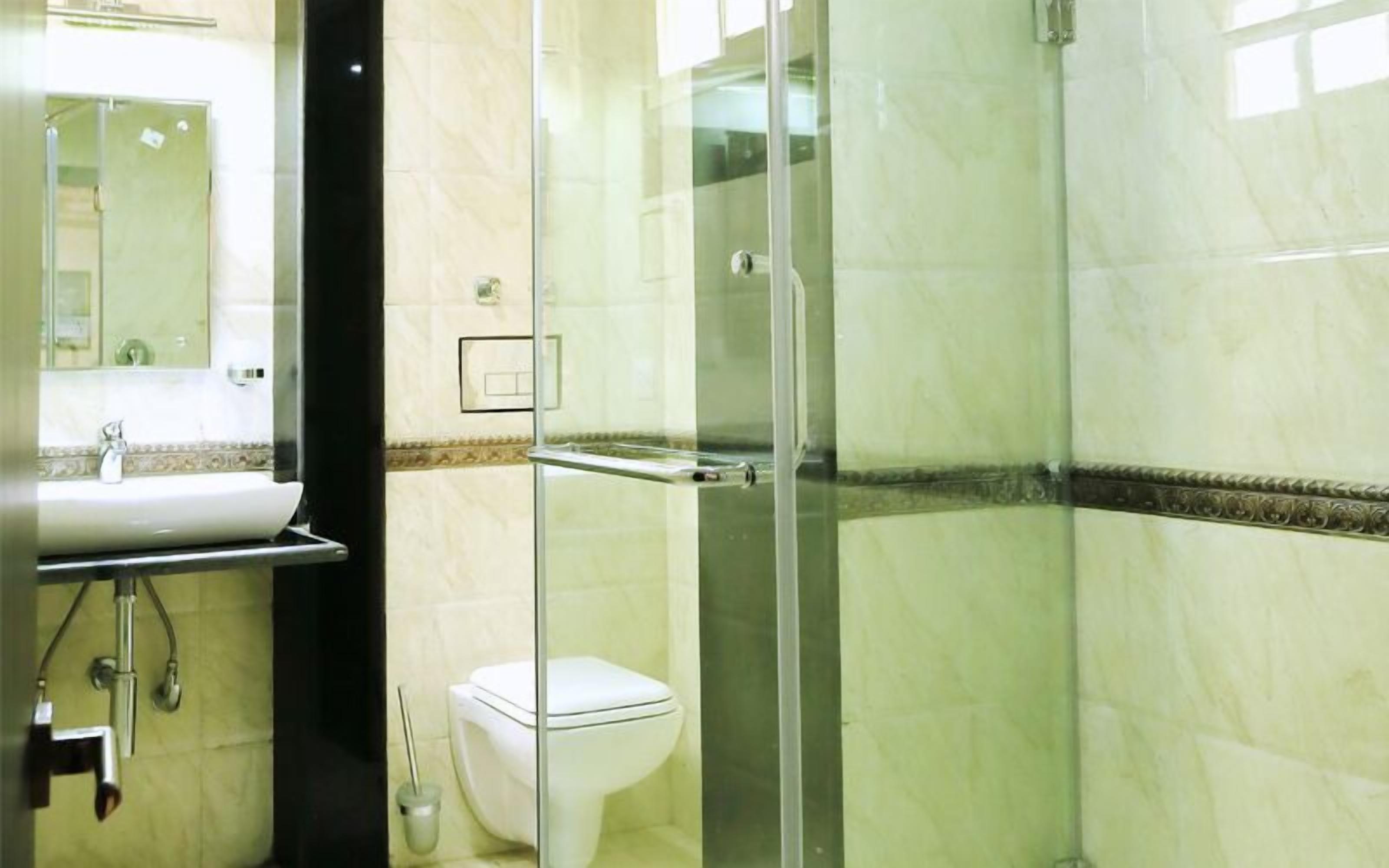A bathroom with a glass-enclosed shower, a white toilet, and a sink with a mirror above it.