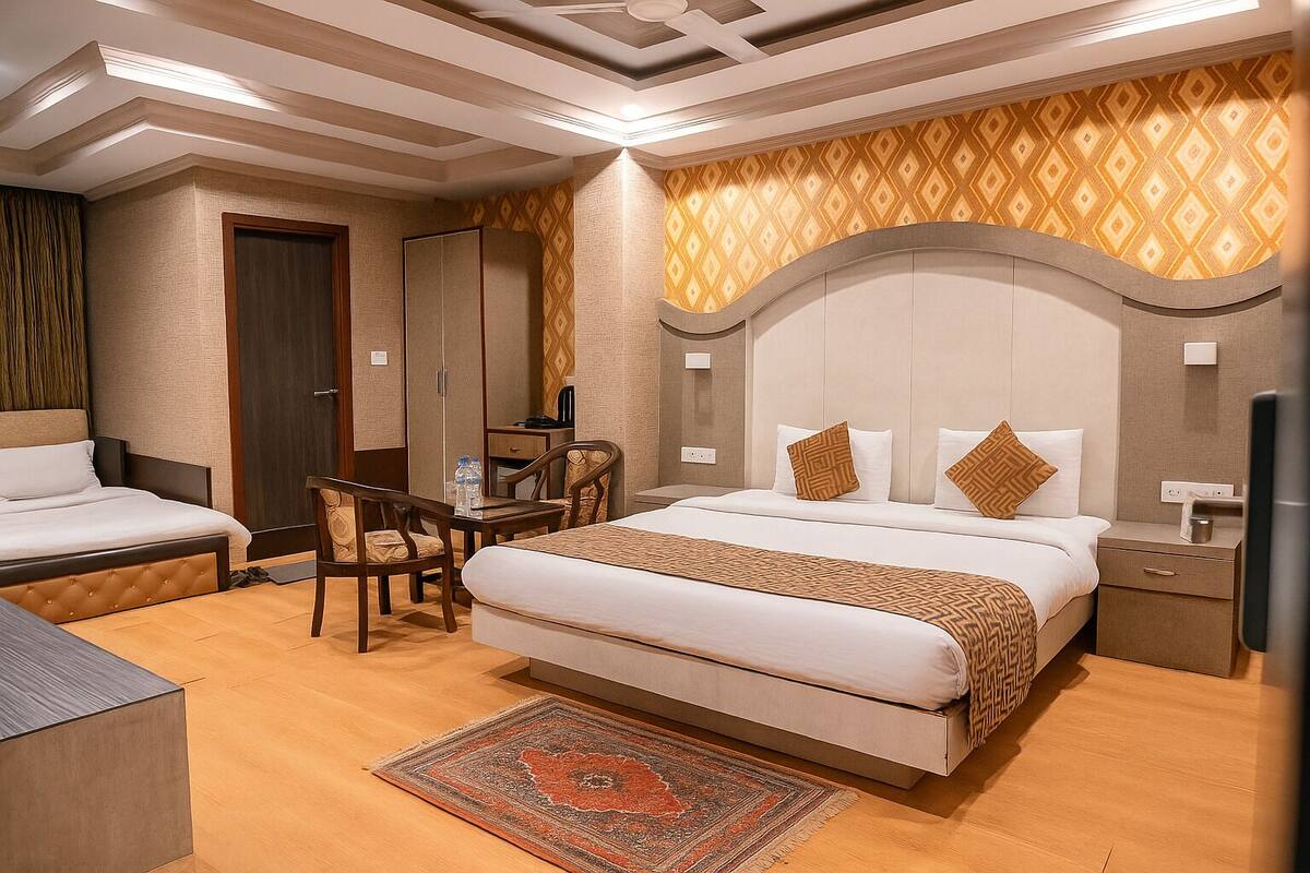 A hotel room with a large bed, a desk, a chair, a wardrobe, and a television.