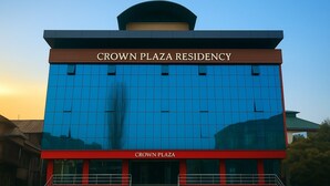 The exterior of Crown Plaza Residency, featuring a modern architectural design with a prominent glass facade and a red and brown color scheme. - Crown Plaza Residency (Srinagar)