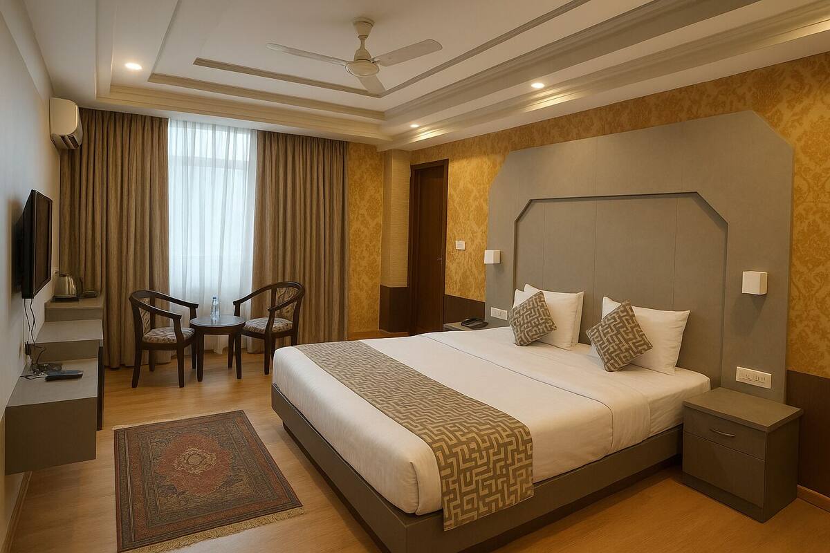 A hotel room with a large bed, a desk with a chair, a television, and a ceiling fan.