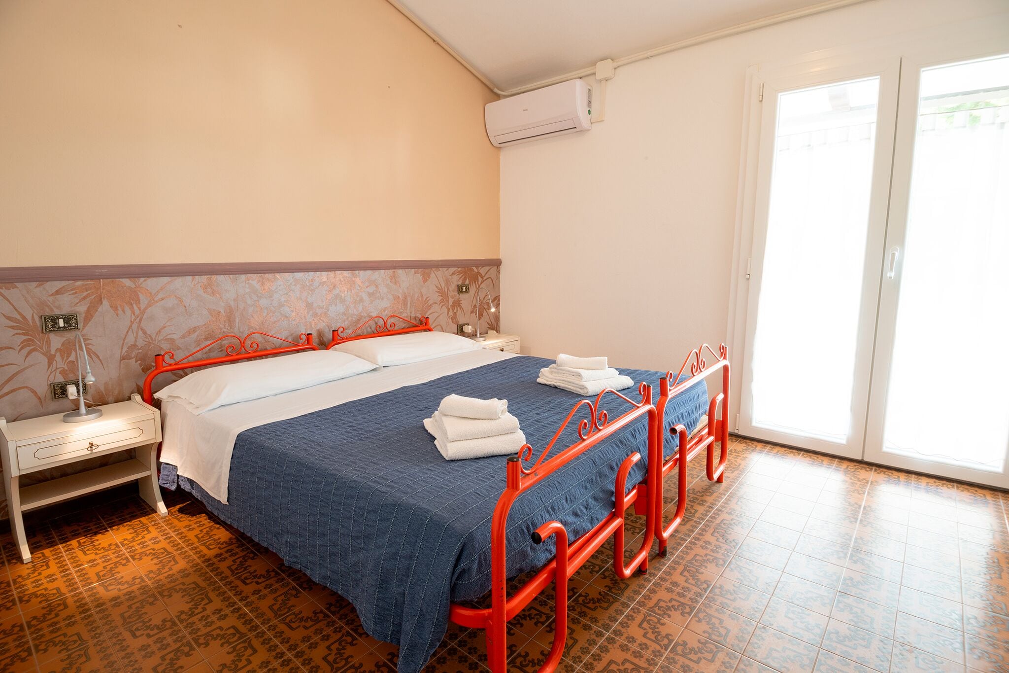 Ein Hotelzimmer mit Bett, Nachttisch, Klimaanlage und Fenster mit Blick.