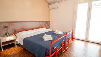 Ein Hotelzimmer mit Bett, Nachttisch, Klimaanlage und Fenster mit Blick.
