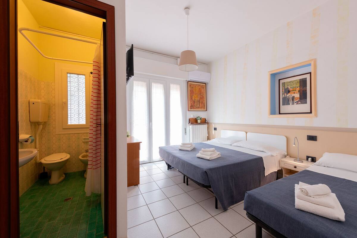 Una habitación de hotel con dos camas, un baño y vistas al exterior.