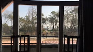 A room with a large arched window overlooking a park with trees and a paved area. - Hotel La Villa (Cervia)