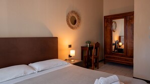 A hotel room with a bed, bedside table, lamp, chair, and a large mirror. - Hotel La Villa (Cervia)