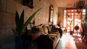 A vintage-style living room with a sofa, a large plant, a chandelier, and a patterned rug. - Hotel La Villa (Cervia)
