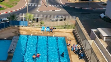 Una piscina al aire libre de temporada, sombrillas, tumbonas