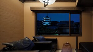 Una stanza con un divano in pelle nera, un tavolino in legno e vista su una pagoda al crepuscolo.