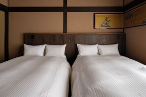 Ett hotellrum med två separata sängar, trägavlar och en tavla på väggen.