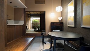 Un interno moderno con una panca in legno, un tavolo rotondo e sedie. Sono presenti luci a parete e un quadro incorniciato.