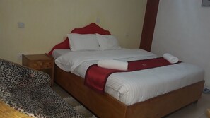 A single-bed room with a wooden frame, white bedding, and a red headboard. - Brooks Lodge (Gilgil)