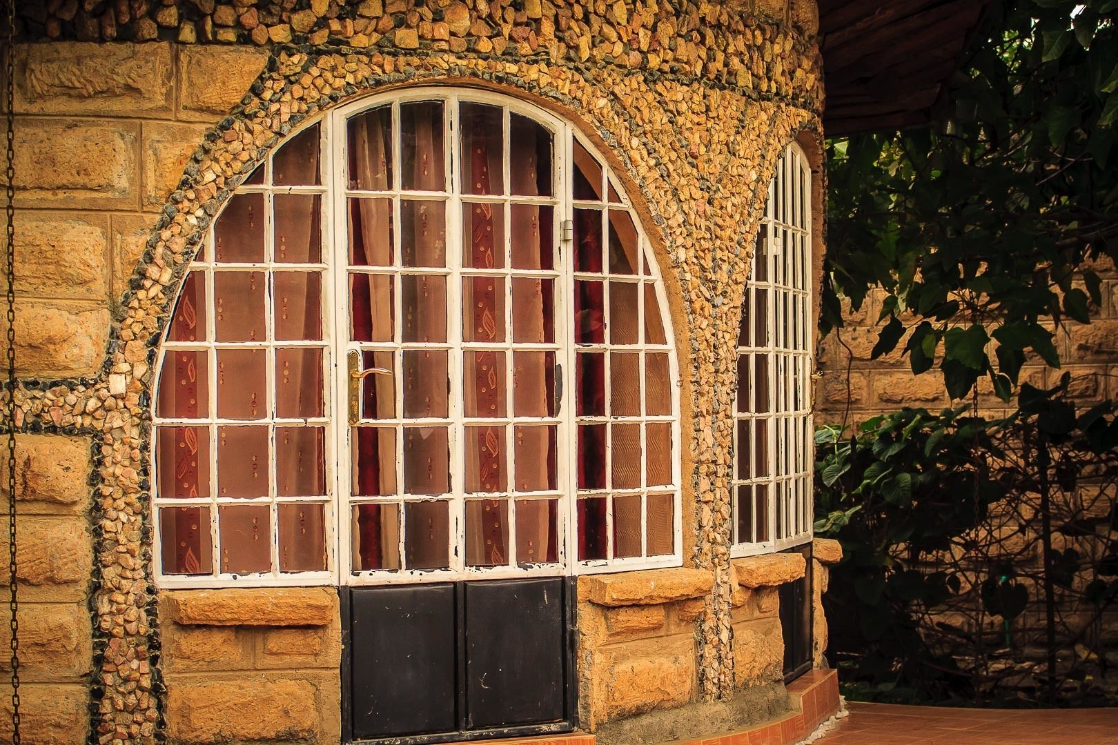 Un edificio de piedra con un amplio ventanal de arco y una ventana más pequeña con rejas.
