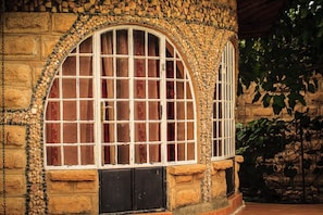 A stone building with a large arched window and a smaller window with bars. - Brooks Lodge (Gilgil)
