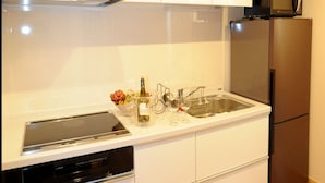Une cuisine moderne avec des meubles blancs, un réfrigérateur en acier inoxydable, un four à micro-ondes et un lave-vaisselle.