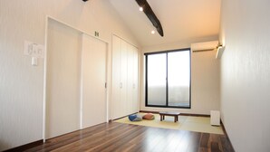 Une pièce avec un plancher en bois, une grande fenêtre, un banc et une petite table.