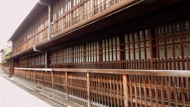 Un bâtiment traditionnel en bois, à plusieurs étages, entouré d’une clôture en bois.