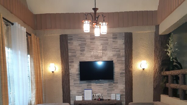 Una sala de estar con dos sofás, una chimenea, un televisor de pantalla plana y un piso de parquet de madera.