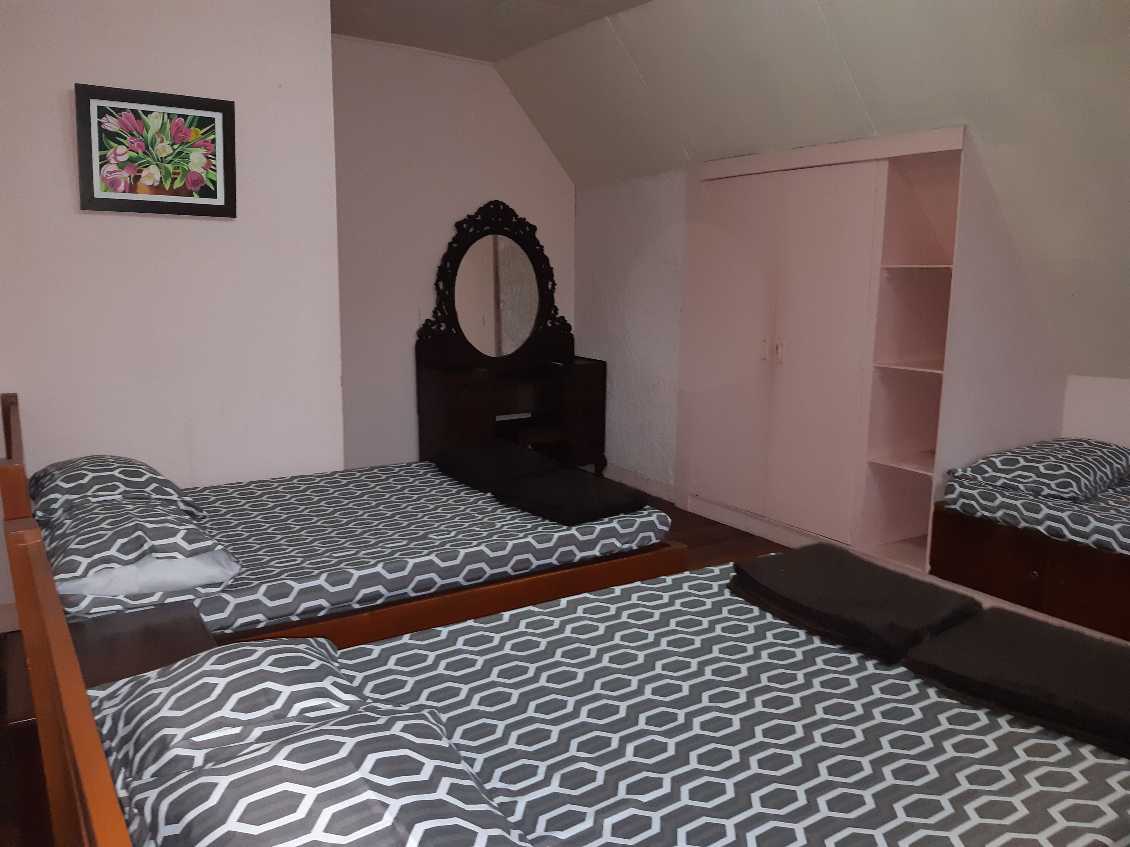 A bedroom with two twin beds, a dresser, a wardrobe, and a mirror.