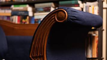 A library chair with a book on it, a bookshelf filled with books, and a wooden headboard.