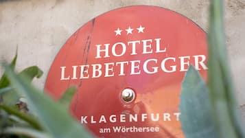Un cartello rosso con scritte bianche che riporta "HOTEL LIEBETEGGER" e "KLANGENFURT am Wörthersee".