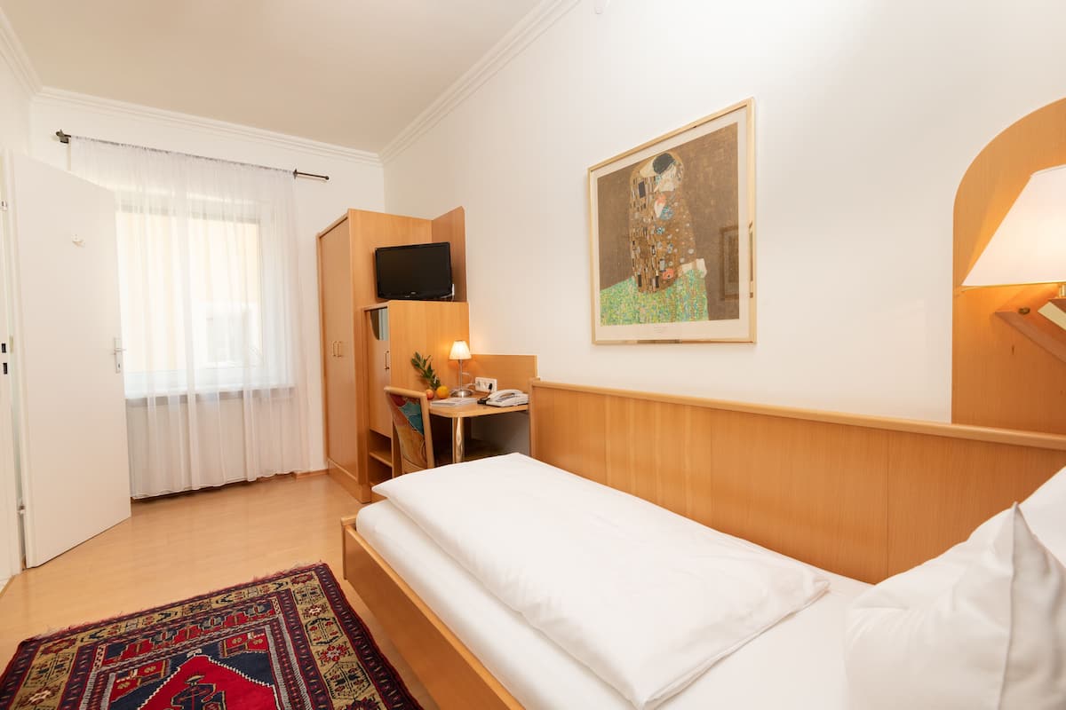 Une chambre d’hôtel avec un lit, un bureau, une télévision, un tableau et une lampe.