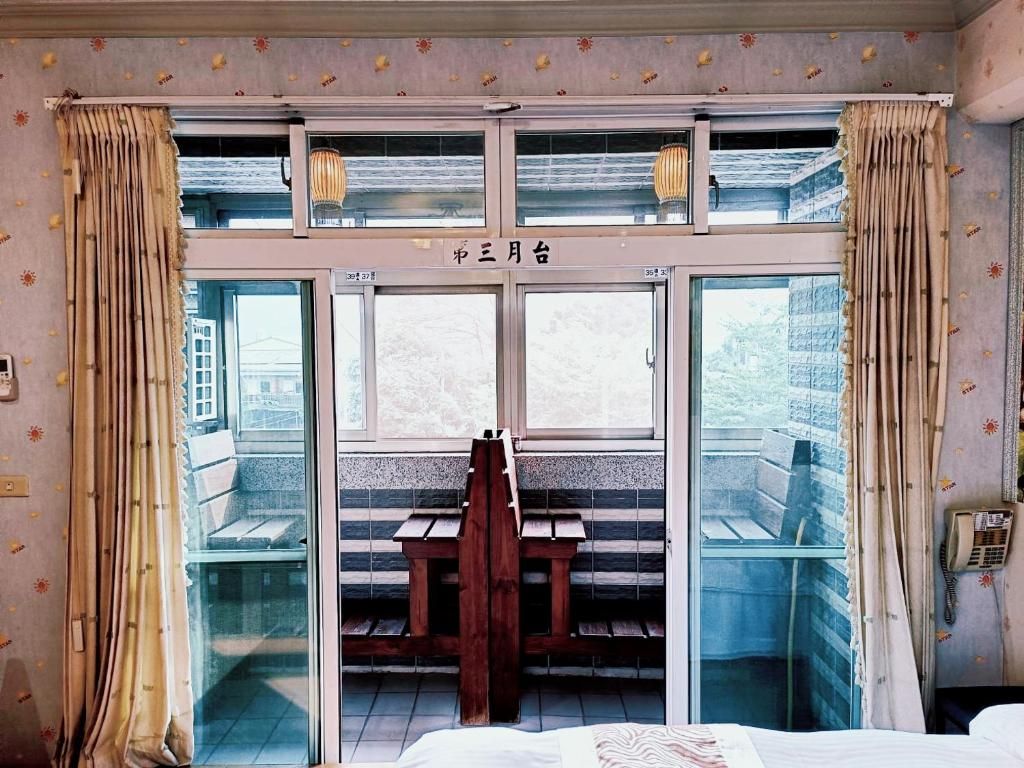 A room with a bed, a wooden bench, and a window with curtains.
