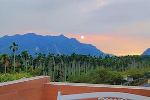 A view of a mountain range with a sunset and palm trees in the foreground. - Jinge Guest House (Jiji)