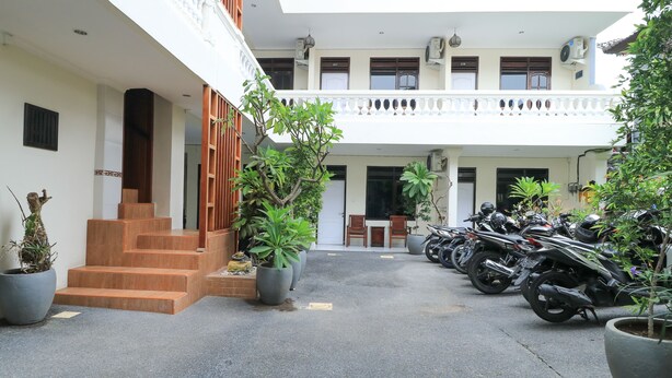 A courtyard with a staircase leading to a second floor, potted plants, and a row of parked motorcycles. - City Garden Bali Dwipa Hotel, Kuta (Kuta)