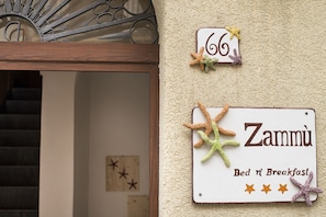 Un panneau indiquant le numéro 66 et le nom « Zammu », désignant une pièce ou un établissement.