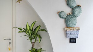 A potted plant in a white pot on a tiled floor with blue and white patterns, a white door with a star decoration, and a wall-mounted cactus planter. - zammu bed and breakfast (Castellammare del Golfo)