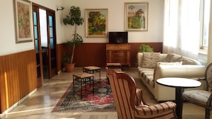 Una sala de estar con sofá, sillones, una mesita, televisor y una planta en maceta.