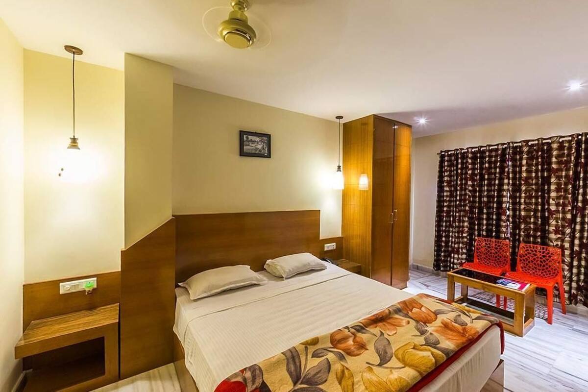 Une chambre d’hôtel avec un grand lit, des tables de chevet, une petite table avec des chaises et une fenêtre recouverte de rideaux.