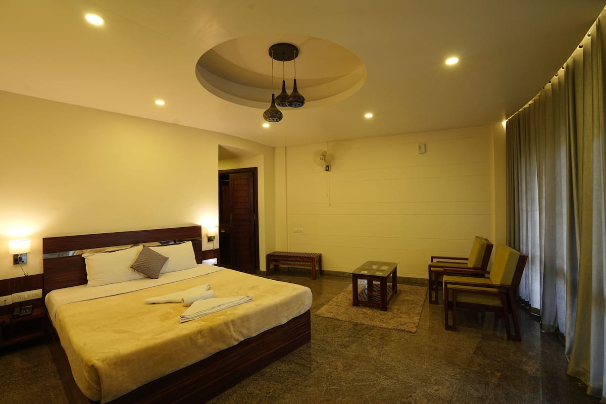 A hotel room with a large bed, bedside table, and a seating area with chairs and a small table.