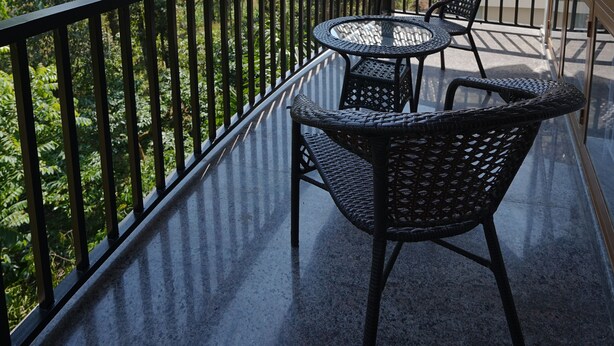 En balkon med udsigt over et bjerglandskab, med et overdækket område med et bord og stole.