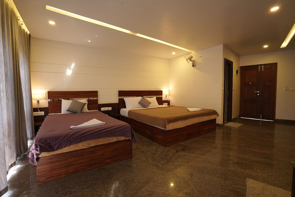 A hotel room with two wooden beds, a large mirror, and a ceiling light fixture.