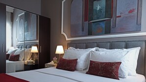 A hotel room with a large bed, a nightstand with a lamp, a mirror, and a painting on the wall. - Tiepolo Galleria Palatina (Thessaloniki)