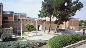 A modern building with a brick facade, a central courtyard with trees, and a clear sky. - Tiepolo Galleria Palatina (Thessaloniki)