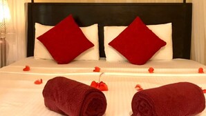 Ein Hotelzimmer mit einem Bett, zwei roten Kissen und zwei zusammengerollten Handtüchern auf dem Bett.