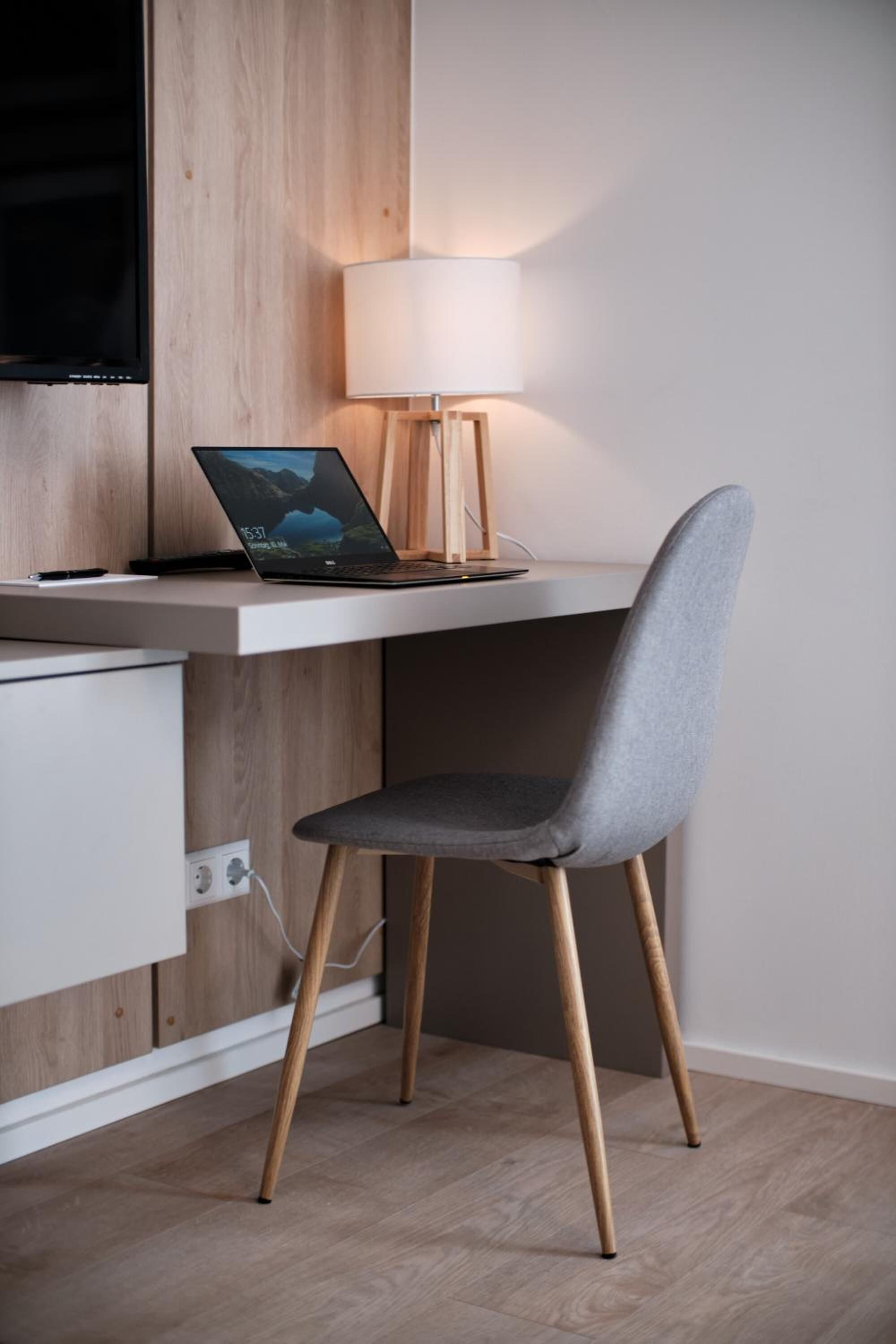 Un espace de travail moderne avec un ordinateur portable sur un bureau, une lampe et une chaise.
