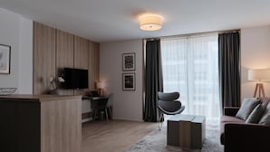 A modern living room with a wooden accent wall, a flat-screen TV, a dining area, and a sofa. - Aparthotel Cosy (Stuttgart)
