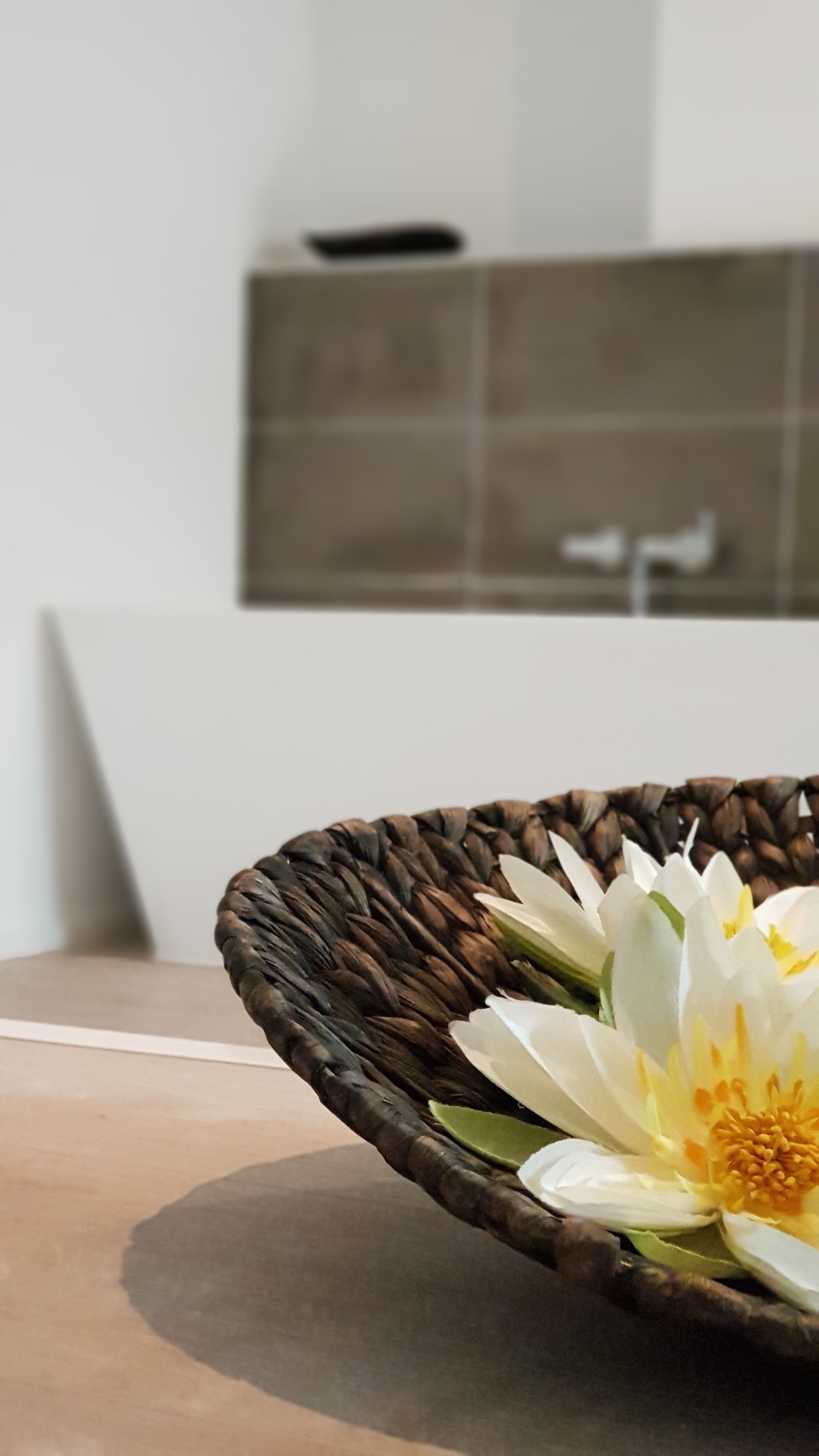 A woven basket with a white flower on a table.