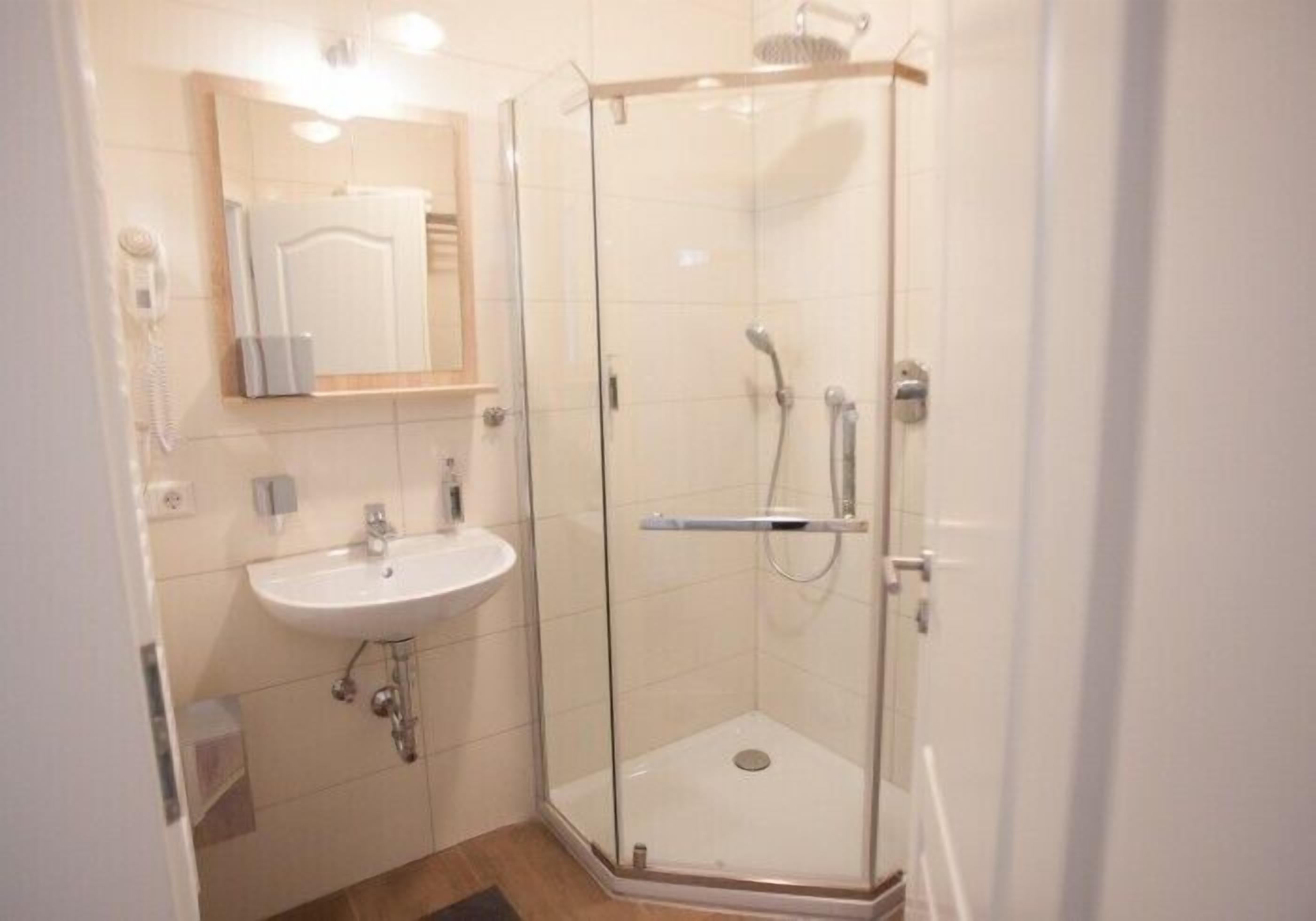 A modern bathroom with a glass-enclosed shower, a white sink, and a mirror above the sink.